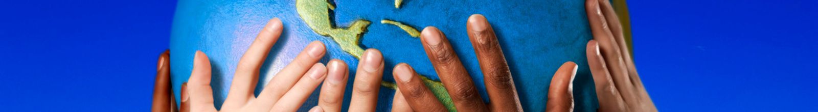 A group of diverse hands hold up a model of the Earth 
