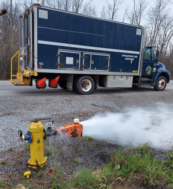 Town of Fort Erie Truck parked on the road with a fire hydrant getting flushed out with water