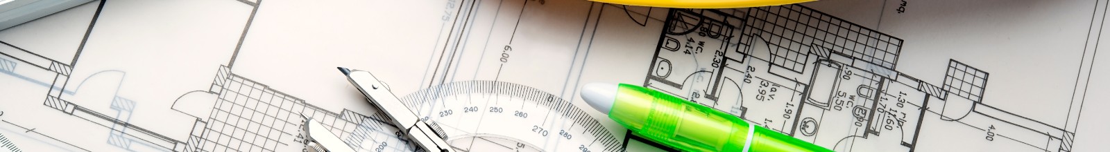 A building plan lays out on a table with office supplies