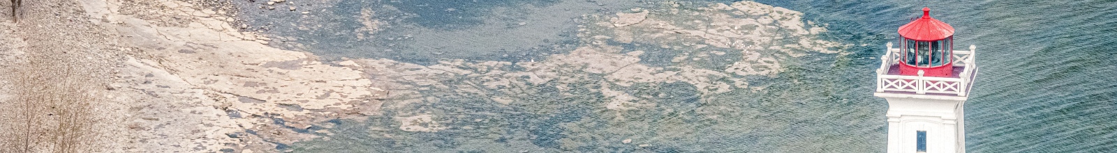 A tall white building with a rocky shoreline below 