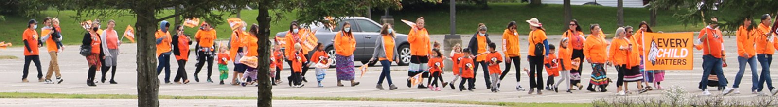 Group of people in orange shirts parading to celebrate National Truth and Reconciliation Day