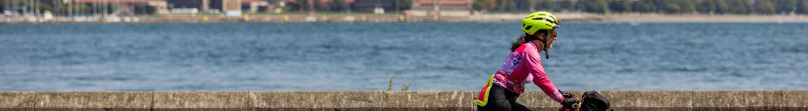 A lady rides a bike along the waterfront