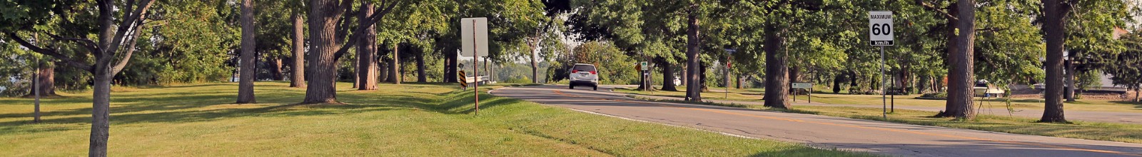 A car drives along on a long road beside the Niagara River