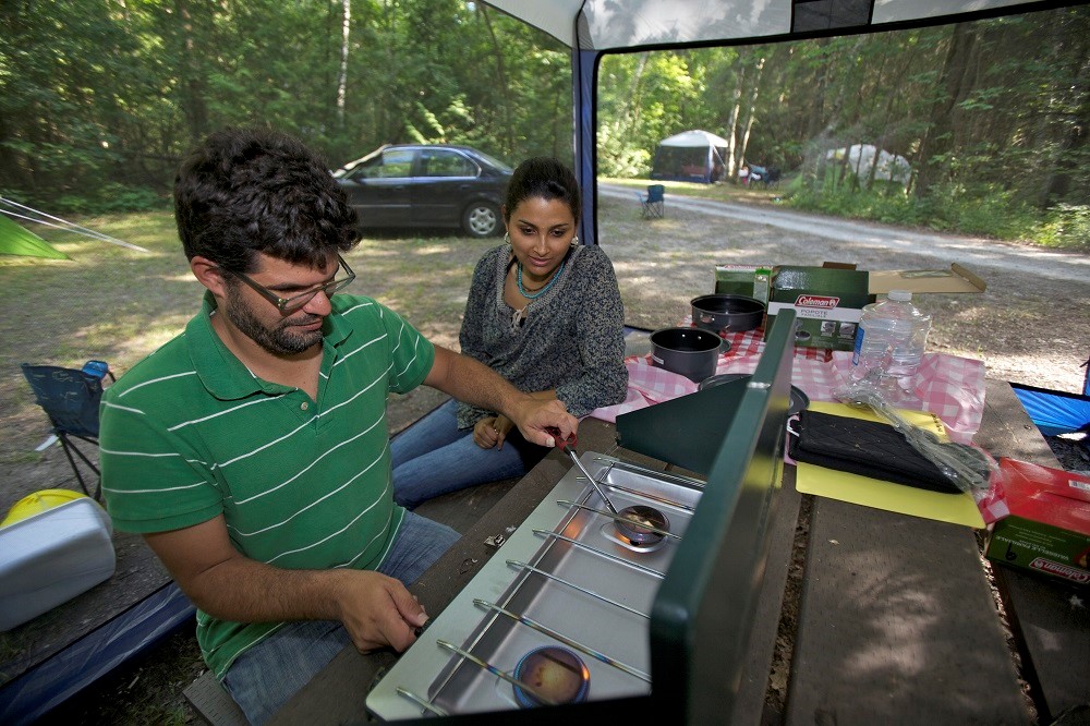 Two people cook on a portable gas grill
