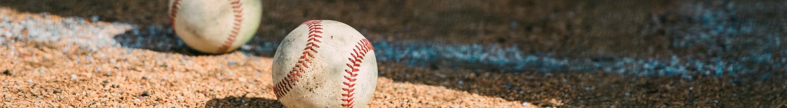 A baseball in the dirt on a sunny day