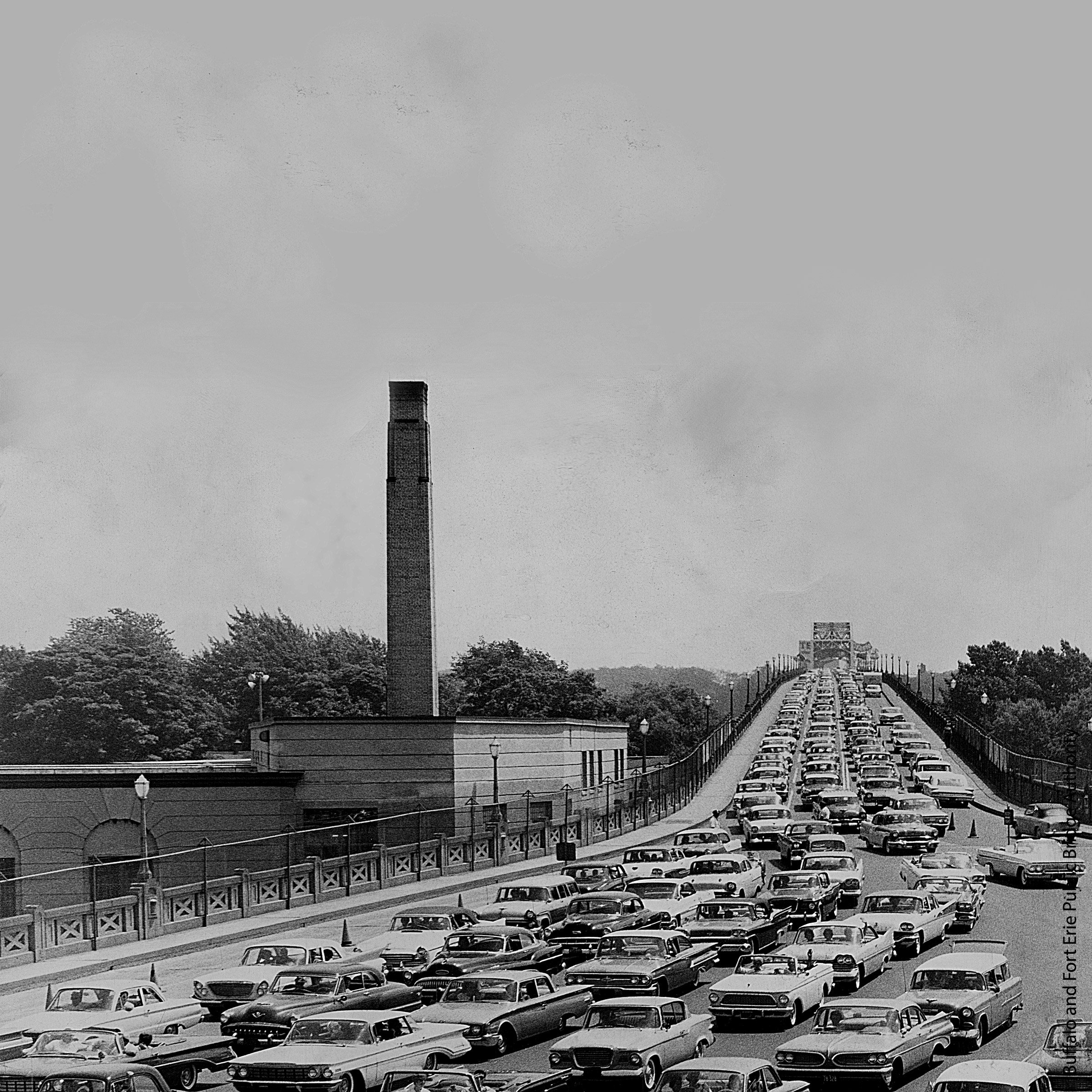 Multiple Lines of cars in lanes coming off a large bridge.