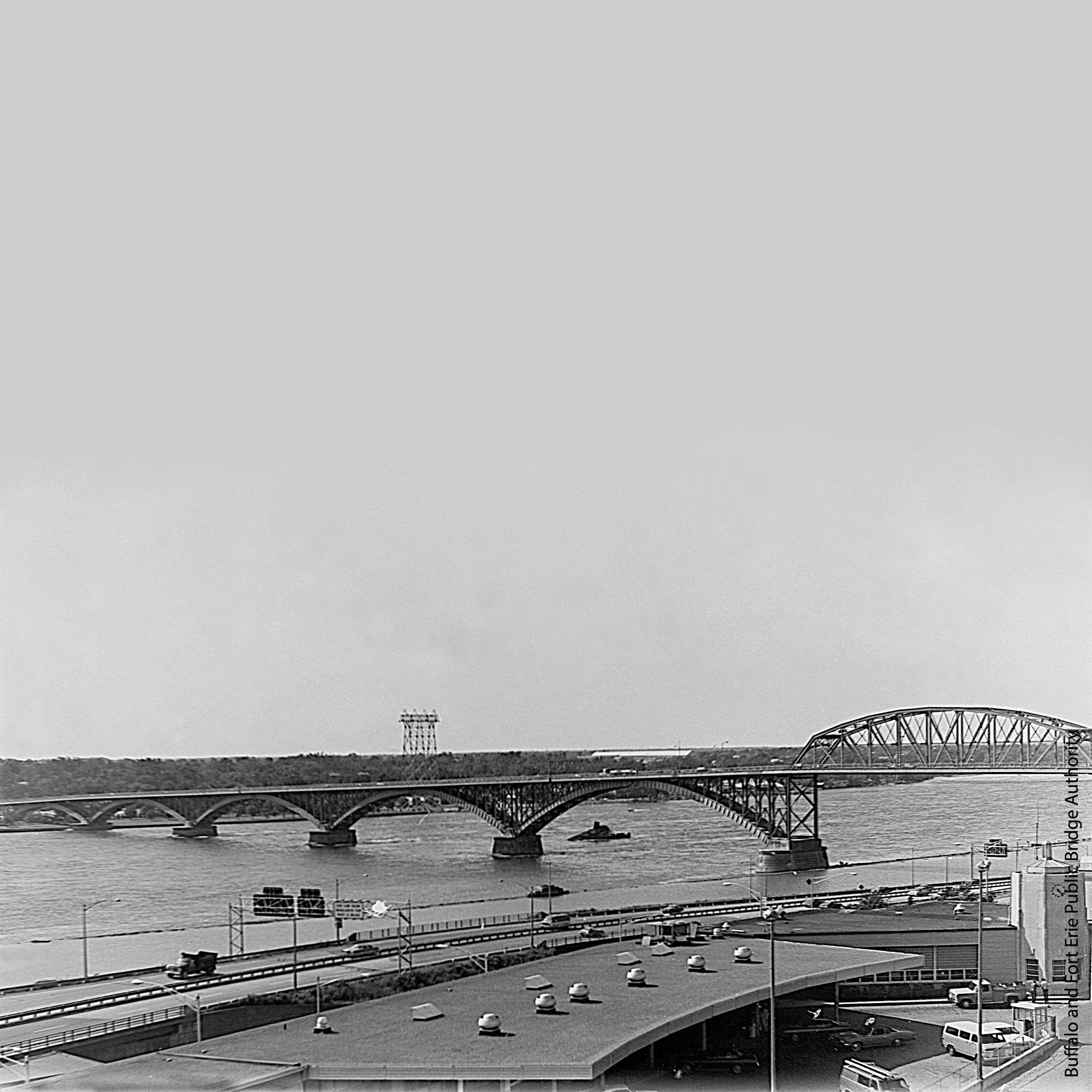 A large bridge running over a highway and large river.