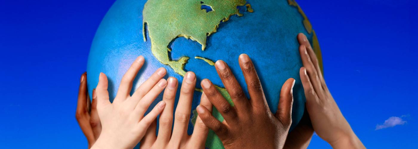 A diverse group of hands hold up a diorama of the Earth  