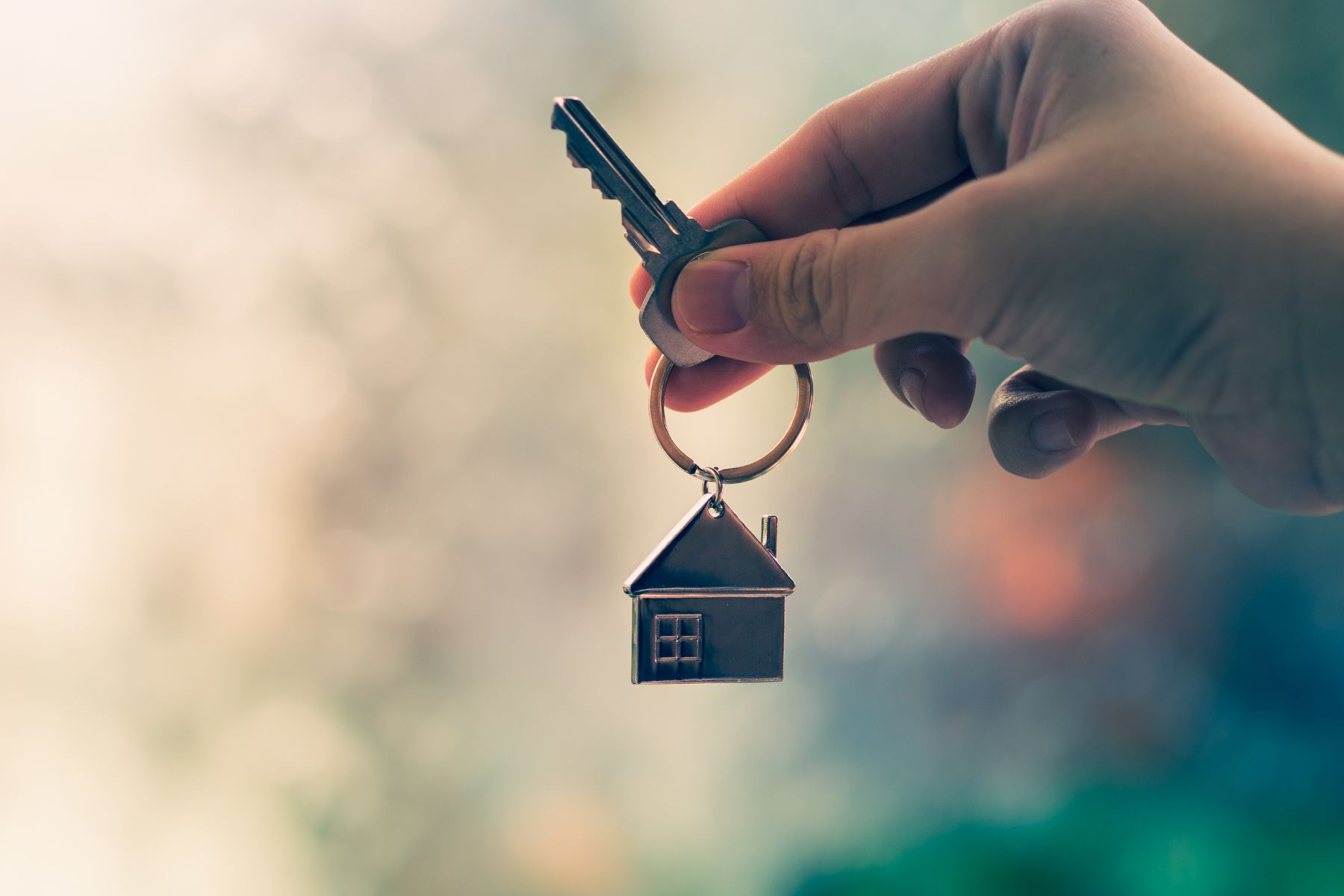 A keychain shaped like a house hangs on a key