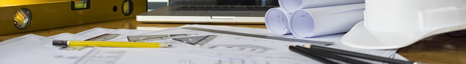 A workstation with pens and plans and a hard hat