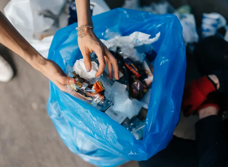 A person putting trash into a garbage bag