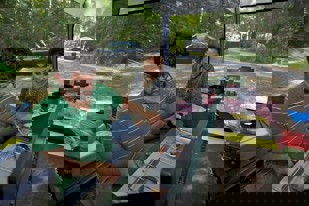 Two people cook on a portable gas grill